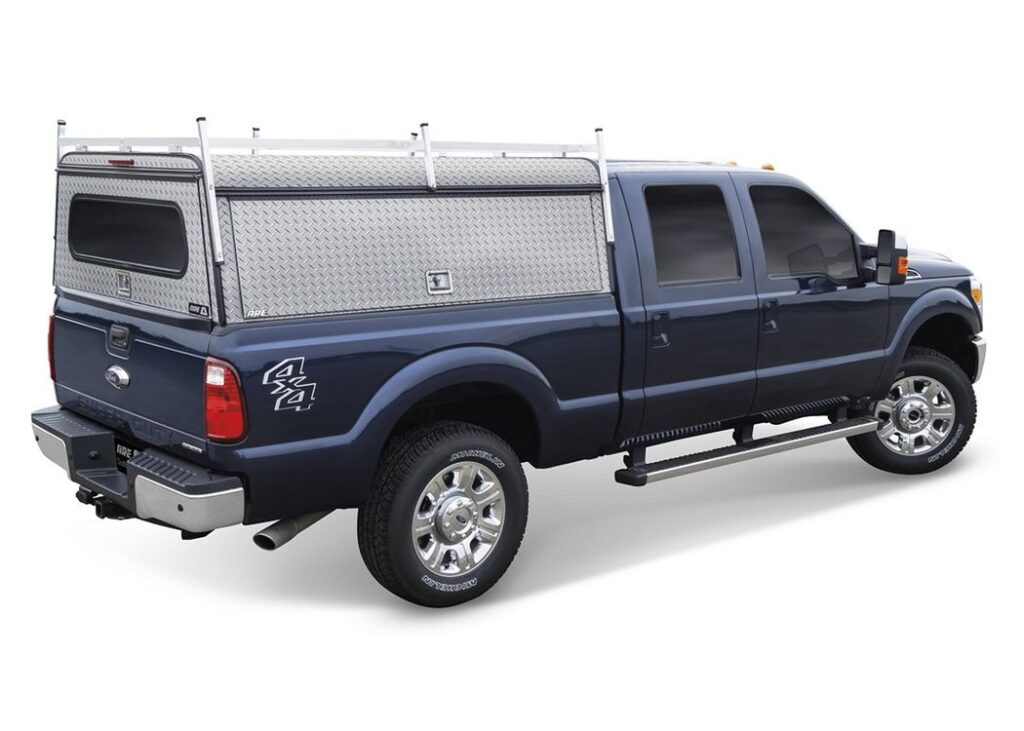 A.R.E. Diamond Edition DCU diamond-plate aluminum work cap with a roof rack on a blue Ford Super Duty