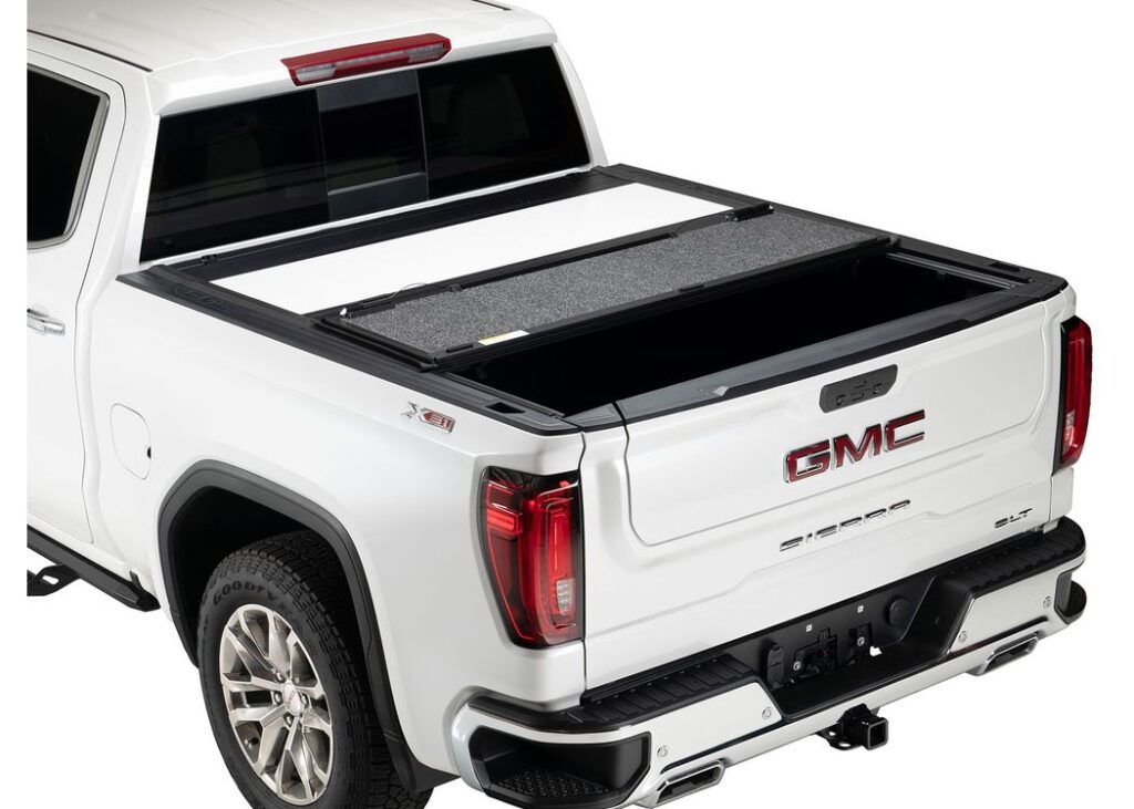 A.R.E. Fusion hard tri-fold tonneau cover, partly folded open, on a white GMC Sierra 1500